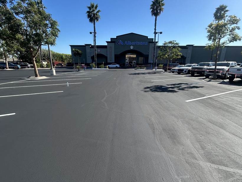 Large grocery anchored center parking lot after full seal coat and striping
