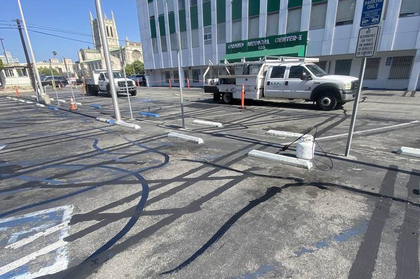 Crew laying out fresh parking stall striping at an office campus